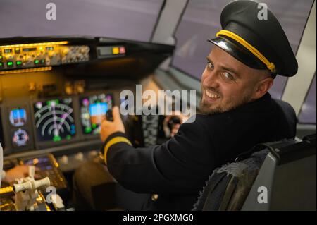 L'uomo caucasico sorrise mentre era seduto in un simulatore di volo. Pilota nel cockpit. Foto Stock