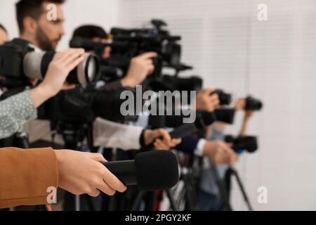 Gruppo di giornalisti con macchine fotografiche in attesa di persona ufficiale al chiuso, primo piano Foto Stock