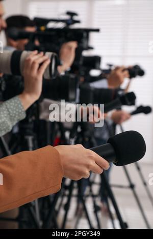 Gruppo di giornalisti con macchine fotografiche in attesa di persona ufficiale al chiuso, primo piano Foto Stock