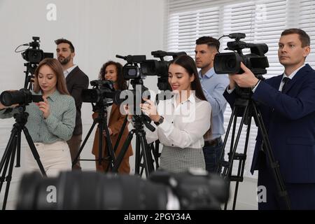 Gruppo di giornalisti con macchine fotografiche in attesa di persona ufficiale al chiuso Foto Stock