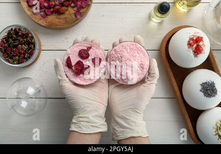 Donna in guanti che fa bomba da bagno al tavolo bianco, vista dall'alto Foto Stock