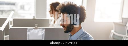 Uomini d'affari che lavorano insieme in un ufficio luminoso, seduti alla scrivania Foto Stock