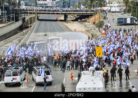 Tel Aviv, Israele. 23rd Mar, 2023. I manifestanti israeliani contro la riforma con le bandiere israeliane sono stati spruzzati da cannoni d'acqua della polizia nel tentativo di liberare l'autostrada di Ayalon bloccata durante la manifestazione. Migliaia di manifestanti contro la revisione legale hanno bloccato l'autostrada Ayalon di Tel Aviv. La polizia ha usato cannoni ad acqua per disperderli. Credit: SOPA Images Limited/Alamy Live News Foto Stock