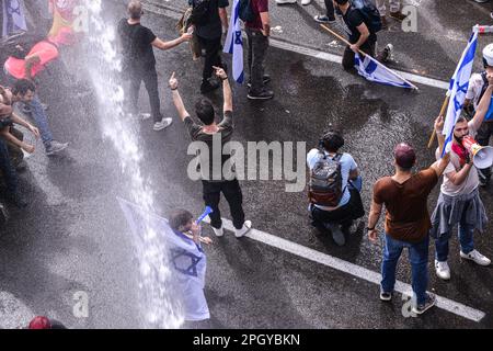 Tel Aviv, Israele. 23rd Mar, 2023. I manifestanti israeliani contro la riforma con le bandiere israeliane sono stati spruzzati da cannoni d'acqua della polizia nel tentativo di liberare l'autostrada di Ayalon bloccata durante la manifestazione. Migliaia di manifestanti contro la revisione legale hanno bloccato l'autostrada Ayalon di Tel Aviv. La polizia ha usato cannoni ad acqua per disperderli. Credit: SOPA Images Limited/Alamy Live News Foto Stock