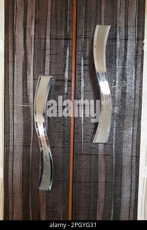 Primo piano di maniglie metalliche e lucenti per porte di guardaroba laminato Foto Stock