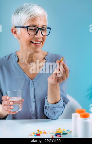 Donna anziana che prende il supplemento dietetico Foto Stock