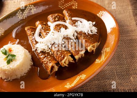 Enmoladas di pollo. Conosciuti anche come mole poblano enchiladas, sono un tipico piatto messicano che è molto popolare in Messico e nel resto del mondo. Foto Stock