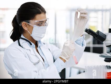 Iniziamo con il prossimo esperimento. un giovane scienziato che indossa guanti protettivi mentre lavora in laboratorio. Foto Stock