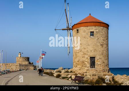Tre mulini a vento sul molo con la fortezza di Agios Nikolaos, il porto di Mandraki, la città di Rodi, la Grecia Foto Stock