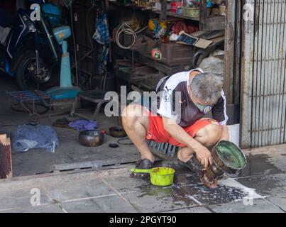 SAMUT PRAKAN, THAILANDIA, 04 2023 FEBBRAIO, l'uomo per strada pulisce il vassoio con il piedistallo per praticare il buddismo Foto Stock