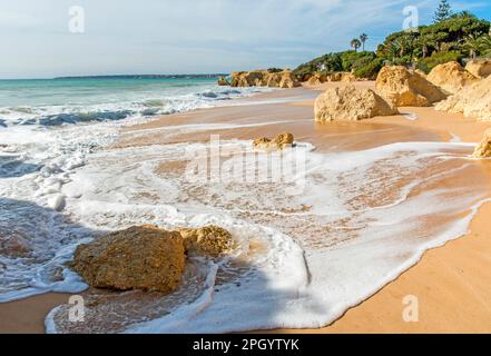 Onde atlantiche rotolano a riva presso la deserta spiaggia di Praia da Galé vicino Albufeira, Algarve Portogallo Foto Stock