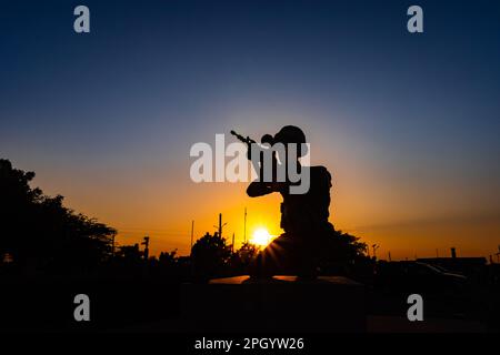 soldato isolato retro illuminato statua con pistola e cielo drammatico da diverse angolazioni alla sera Foto Stock