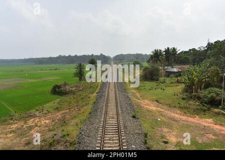 Un tratto ferroviario rurale che passa attraverso un villaggio in Tripura , India . Foto Stock