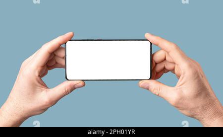 Cornice mock-up per telefono cellulare, schermo orizzontale per smartphone in mani maschili su sfondo blu. Foto Stock