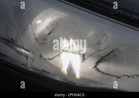 Il faro per auto congelato è acceso, foto ravvicinata con messa a fuoco selettiva Foto Stock