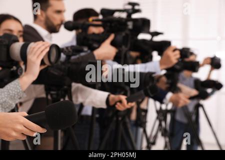 Gruppo di giornalisti con macchine fotografiche in attesa di persona ufficiale al chiuso, primo piano Foto Stock