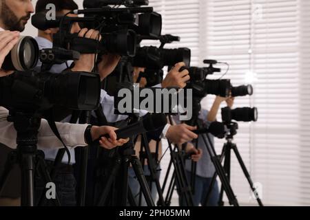 Gruppo di giornalisti con macchine fotografiche in attesa di persona ufficiale al chiuso, primo piano Foto Stock