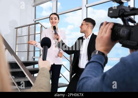 Felice donna d'affari che parla con i giornalisti al coperto Foto Stock