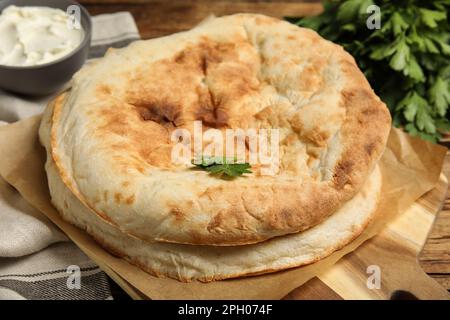 Pagnotte di delizioso pane pita fatto in casa su tavola di legno, primo piano Foto Stock