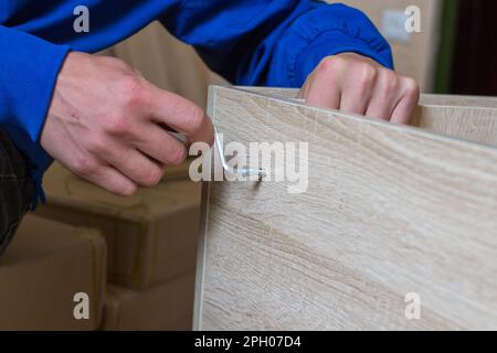 Uomo che monta il fissaggio di mobili con una chiave esagonale Foto Stock