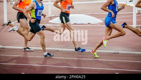 Atleti di gruppo in corsa a distanza media, scarpe da running Nike e Adidas Spikes, giochi sportivi estivi Foto Stock