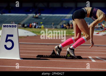 Sprinter femminile che corre da blocchi di partenza in atletica, abbigliamento da running Nike e lane marker mondo, maniche a compressione Compressport Foto Stock