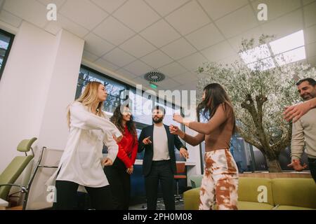 Gruppo intergenerazionale di persone di successo che festeggiano i risultati e i risultati dei progetti alla fine del mese. Ballano in moder Foto Stock