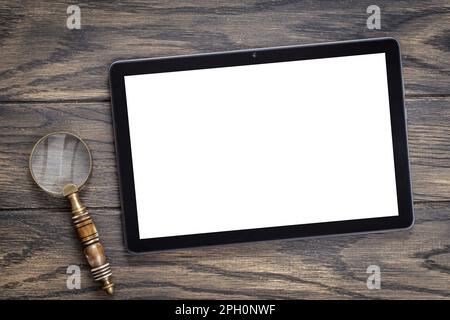 Mockup con tablet e lente d'ingrandimento sul tavolo. Informatica, analisi, concetto di ricerca Foto Stock