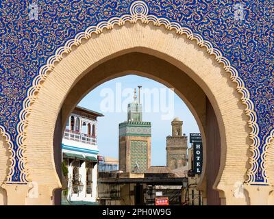 Minareto del Bou Inania Madrasa visto attraverso l'iconico Bab Bou Jeloud a Fez, Marocco in un pomeriggio di sole Foto Stock