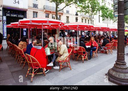 05-14-2016 PARIGI. Caffè all'aperto sulla strada Champ-Elysees e persone che si siedono lì sotto ombrelloni rossi Foto Stock