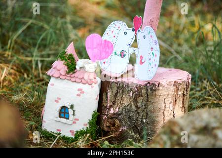 Due piccoli hedgehogs amanti carta artigianato vicino piccola casa bambola su sfondo verde legno, carino bambini artigianato circa l'amore. Riccio di carta artigianale in verde g Foto Stock