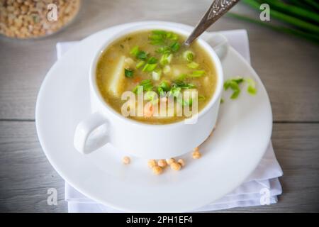 zuppa di piselli secchi in un piatto con erbe aromatiche, su un tavolo di legno. Foto Stock