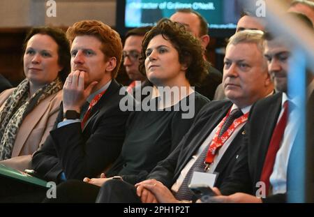 (Secondo da sinistra a destra) Matthew o'Toole, Claire Hanna MP e Patsy McGlone MLA guardano come il leader dell'SDLP Colum Eastwood (non illustrato) parla durante la conferenza primaverile del Partito socialdemocratico e laburista (SDLP) a St Columb's Hall a Derry. Data immagine: Sabato 25 marzo 2023. Foto Stock