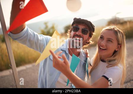 Giovane coppia che prepara la festa in auto all'aperto in campeggio, caravan vacanza viaggio. Foto Stock