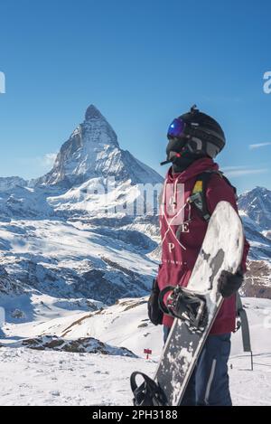 Giovane snowboarder che trascorre le vacanze invernali a Zermatt, vicino alla famosa cima del Cervino. Foto Stock