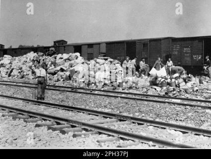 La caserma 'Kanada' nel campo di concentramento di Auschwitz, Polonia occupata dai tedeschi, durante l'Olocausto. I prigionieri ordinano i casi e le borse di coloro che sono stati inviati alla camera a gas all'arrivo. I magazzini sono stati chiamati 'Kanada' perché contenevano gli effetti saccheggiati dei prigionieri e sono stati considerati all'interno del campo come la terra di abbondanza. Foto Stock