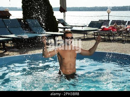 Bell'uomo che si diverte nella piscina all'aperto il giorno d'estate Foto Stock