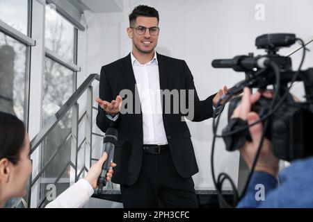 Felice uomo d'affari che parla con i giornalisti al coperto Foto Stock
