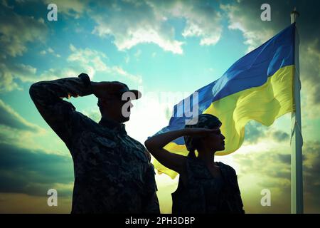 Fermare la guerra in Ucraina. Silhouette di soldati che saluta alla bandiera Ucraina all'aperto Foto Stock