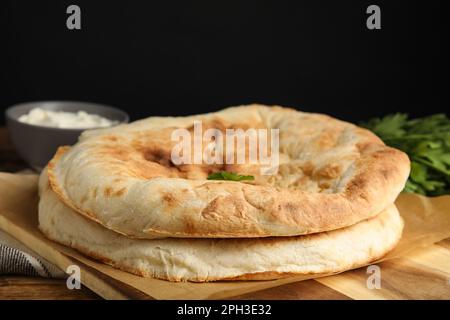 Pagnotte di delizioso pane pita fatto in casa su tavola di legno, primo piano Foto Stock