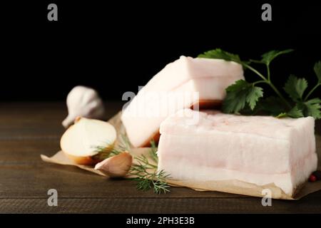 Gustoso maiale salato con erbe, cipolla e aglio su tavola di legno, spicchio Foto Stock