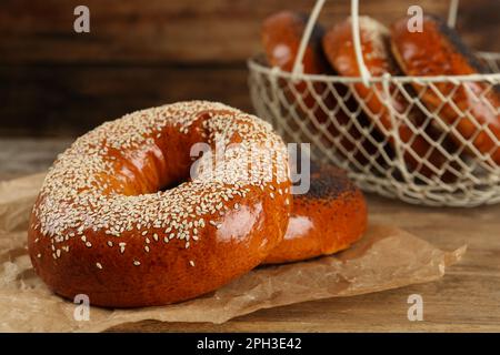 Deliziosi bagel freschi con semi di papavero e sesamo su un tavolo di legno Foto Stock