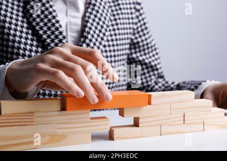 Donna d'affari costruzione ponte con blocchi di legno a tavola, guardaroba. Connessione, relazioni e concetto di trattativa Foto Stock