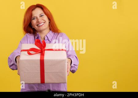 Donna matura arrossata che consegna un regalo per il giorno della madre Foto Stock