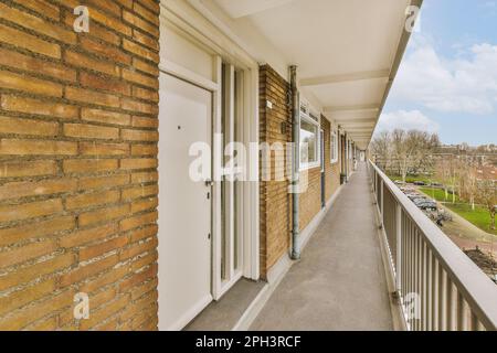 un balcone con pareti in mattoni e rifiniture bianche sulla parete esterna, che si affaccia sulla strada da un appartamento Foto Stock