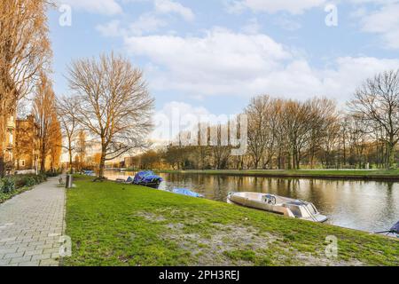 alcune barche parcheggiate sul lato di un fiume con alberi sullo sfondo e gli edifici lungo il bordo dell'acqua Foto Stock