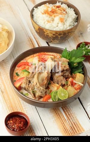 Soto Tangkar, cucina Betawi specialità Soto a base di agnello o costolette di manzo cotte in sottile zuppa di latte di cocco speziata con curry rosso. Foto Stock