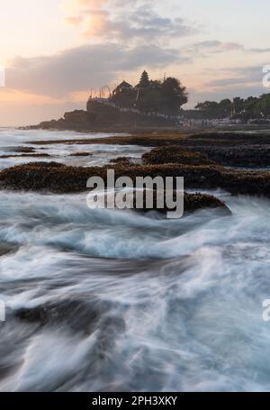Wave and Tanah Lot Temple a Bali, al tramonto Foto Stock