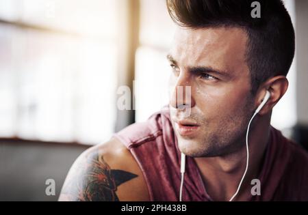 La musica lo motiva per il suo prossimo allenamento. un bel giovane in palestra. Foto Stock