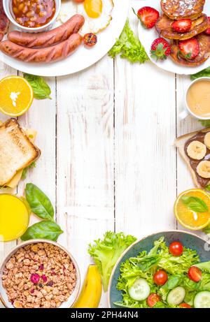 Assortimento di scelte per la colazione. Colazione all'inglese, salsicce, uova fritte, pancetta, insalata, muesli, sandwich al formaggio, frittelle dolci, crema al cioccolato e. Foto Stock